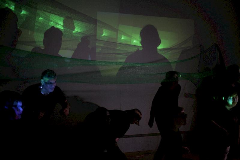 Tanzgruppe in einem dunklen Raum vor Leinwand mit Videoprojektionen
